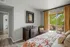 Inviting bedroom with cozy decor, large window opening to a lush balcony view, and warm natural tones.