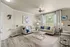 Elegant living room with modern decor, featuring cozy beige sofas, plush cushions, and a chic coffee table. Natural light flows through large windows, highlighting the contemporary art and serene ambiance.