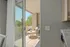 Inviting balcony patio with elegant seating, accessed through sliding glass doors, offering a serene outdoor retreat with lush greenery views.