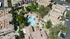 Aerial view of a spacious apartment complex featuring a resort-style pool, lush landscaping, and ample outdoor seating areas.