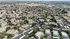 Aerial view of a vibrant residential community featuring neatly arranged apartment complexes, lush green spaces, and a central swimming pool, set amidst a sprawling suburban landscape.