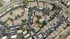 Aerial view of a beautifully planned apartment complex featuring lush greenery, ample parking, and a resort-style pool.