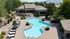 Luxurious outdoor pool area with elegant lounge chairs, surrounded by lush greenery and modern architecture.