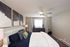 Inviting bedroom featuring a plush bed with decorative pillows, ambient lighting, and modern abstract art.