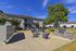 Spacious outdoor common area with comfortable seating, BBQ grill, and lush greenery.