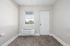 Bright room interior with large window, wooden flooring, and a wall-mounted air conditioning unit.