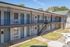 Inviting two-story apartment complex with blue doors, white brick facade, and external staircases.