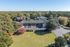 Aerial view of an apartment complex surrounded by lush greenery, ample parking space, and expansive lawns.