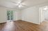 Bright and airy living space with modern wood flooring, ceiling fan, and sliding doors opening to a scenic balcony view.