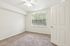 Bright and airy bedroom with plush carpet, large window allowing natural light, and fresh neutral walls, perfect for relaxation.