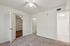 Bright and inviting bedroom with plush carpet, featuring an entrance to an adjacent wooden-floored room and a modern bathroom.