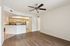 Modern apartment living area with elegant wood flooring, ceiling fan, and an open-plan kitchen with sleek cabinetry.