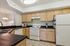 Modern kitchen with sleek black countertops, wooden cabinetry, and integrated appliances in a stylish apartment setting.