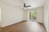 Bright, open living room with elegant wood flooring, ceiling fan, and sliding glass doors leading to a scenic balcony view.
