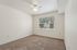Bright and inviting bedroom with plush carpet, ceiling fan, and large window providing natural light and garden views.