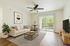 Bright and modern living room with a cozy beige sofa, elegant wall art, and a large window offering a serene garden view, perfect for relaxation and entertaining.