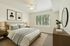Serene bedroom with elegant decor, featuring a cozy bed, modern artwork, and a bright window view.