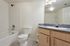 Bright and modern bathroom featuring a sleek vanity with granite countertop, classic white tile bathtub, and contemporary lighting.