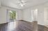Bright living area with elegant wood flooring, ceiling fan, and sliding glass doors opening to a lush green view.