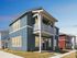 Modern two-story blue townhouse with a charming balcony and elegant design, set against a clear blue sky.