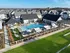 Luxurious apartment complex featuring a sparkling swimming pool, sun loungers, shaded pergolas, and lush green spaces, perfect for relaxation and leisure.