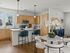 Elegant open-plan kitchen and dining area featuring sleek wooden cabinets, modern appliances, marble dining table, and stylish teal bar stools.