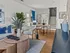Modern living room with stylish decor, featuring a cozy seating area, elegant staircase, and vibrant blue accents.