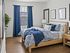Inviting bedroom featuring a cozy bed with plush blue accents, elegant wooden furniture, and a bright window view.