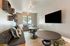 Modern entertainment room with plush seating, decorative wall shelves, and large flat-screen TV, perfect for relaxation.