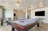 Contemporary game room with sleek pool table, foosball table, and modern lighting, offering a vibrant entertainment space.