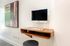 Sleek modern workspace with a wall-mounted computer and a stylish wooden floating desk, complemented by contemporary artwork.