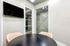 Contemporary conference room with sleek black round table, modern TV, and elegant glass panel walls.