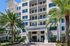 Chic leasing center entrance of a modern apartment building lined with palm trees, showcasing architectural elegance and inviting ambiance.