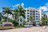 Elegant apartment complex surrounded by lush palm trees under a clear blue sky, featuring modern architecture and inviting outdoor spaces.