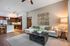 Elegant living room with a modern open kitchen, featuring cozy beige seating, artistic decor, and sleek wooden cabinetry.