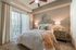 Elegant bedroom featuring a cozy bed with plush pillows, a modern ceiling fan, and soft lighting. The room is brightened by natural light from large vertical blinds and complemented by a stylish mirror and rustic wooden nightstand.