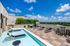 Luxurious rooftop patio with a refreshing pool, stylish loungers, and vibrant greenery, perfect for relaxing under the clear blue sky.