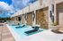 Luxurious rooftop pool area with elegant stone wall design and stylish loungers under a vibrant blue sky.