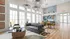 Inviting living space with chic modern decor, featuring a plush gray sofa, stylish geometric wallpaper, and abundant natural light from large windows.