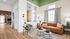 Chic and inviting living room with a stylish leather sofa, modern green accent chair, and elegant decor, bathed in natural light.