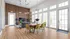 Modern apartment living and dining area featuring tall windows, a stylish wooden accent wall, and vibrant yellow chairs around a sleek table.
