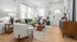 Inviting living room with a modern green couch, stylish wooden coffee table, elegant decor, abundant natural light from large windows, and warm wood flooring.