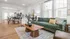 Inviting open-concept living and dining area featuring a stylish green sofa, elegant wooden coffee table, and a modern kitchen with sleek finishes.