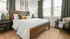 Inviting bedroom with a wooden bed frame, crisp white linens, and stylish green accents, creating a cozy and elegant atmosphere.