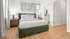 Bright and elegant bedroom with a plush green bed, stylish wooden nightstands, and serene palm leaf artwork, leading to a modern en-suite bathroom.