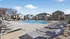 Inviting outdoor pool area with elegant lounge chairs and modern cabanas set against a backdrop of charming houses under a clear blue sky.