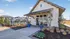 Charming clubhouse entrance with modern design, lush landscaping, and bright blue planters, perfect for welcoming residents.