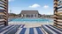 Inviting outdoor pool area with lounge chairs, modern clubhouse, and clear blue skies, perfect for relaxation and entertainment.
