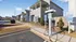 Modern apartment complex with eco-friendly electric vehicle charging stations, surrounded by pristine landscaping and well-maintained walkways under a clear blue sky.