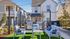 Charming outdoor patio with cozy seating, lush greenery, and modern barbecue grills in a serene neighborhood setting.